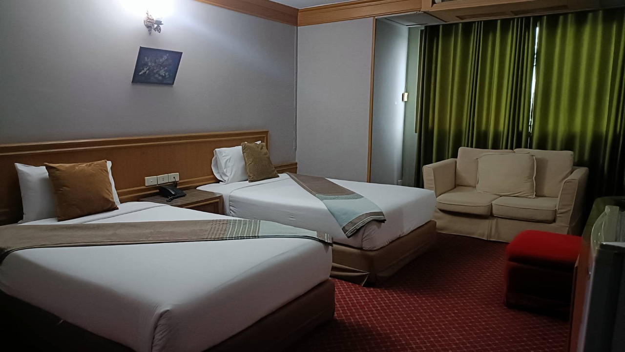 Twin-bed room at Pathumthani Place Hotel with a sofa and red carpet