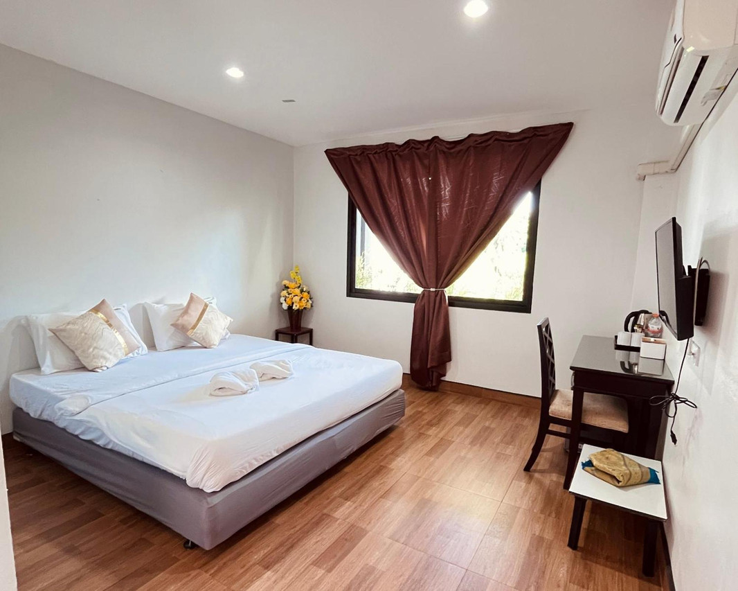 ห้องพักภายในเรียบง่าย เตียงใหญ่ พื้นไม้ลามิเนต แอร์ และทีวี