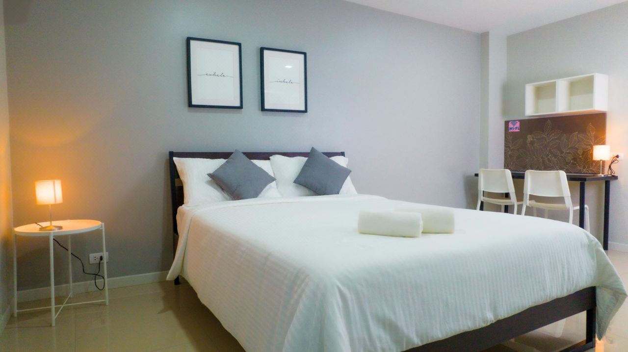 ห้องพัก BM Pattani Apartment เตียงใหญ่ โต๊ะทำงาน และผนังโทนเทาอ่อน
