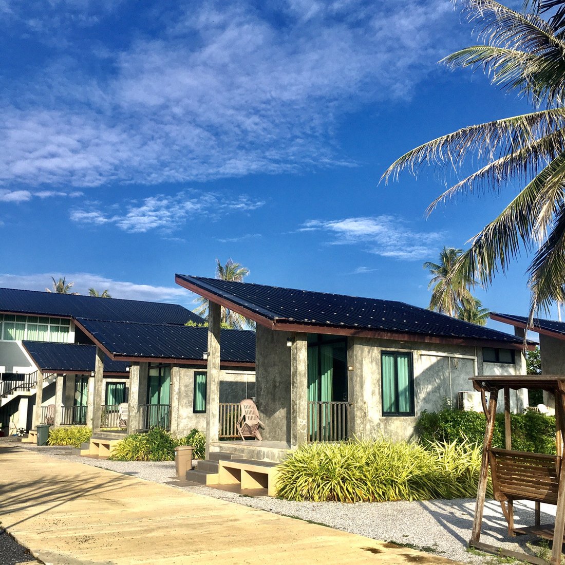 แถวบังกะโลปูนเปลือยของ Nee Ran Nee Resort กับต้นมะพร้าวริมหาด
