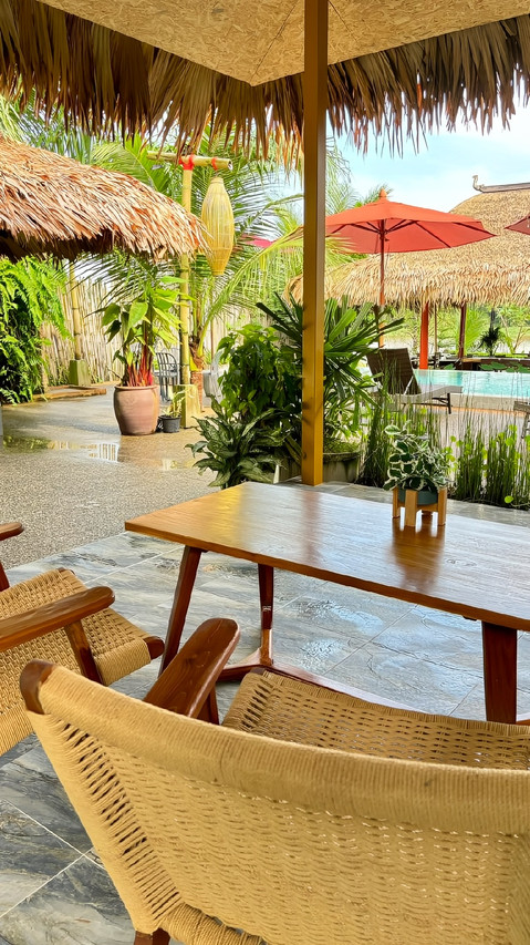 มุมนั่งเล่นริมสระและสวนใต้หลังคามุงจาก Canal Village Pakpra