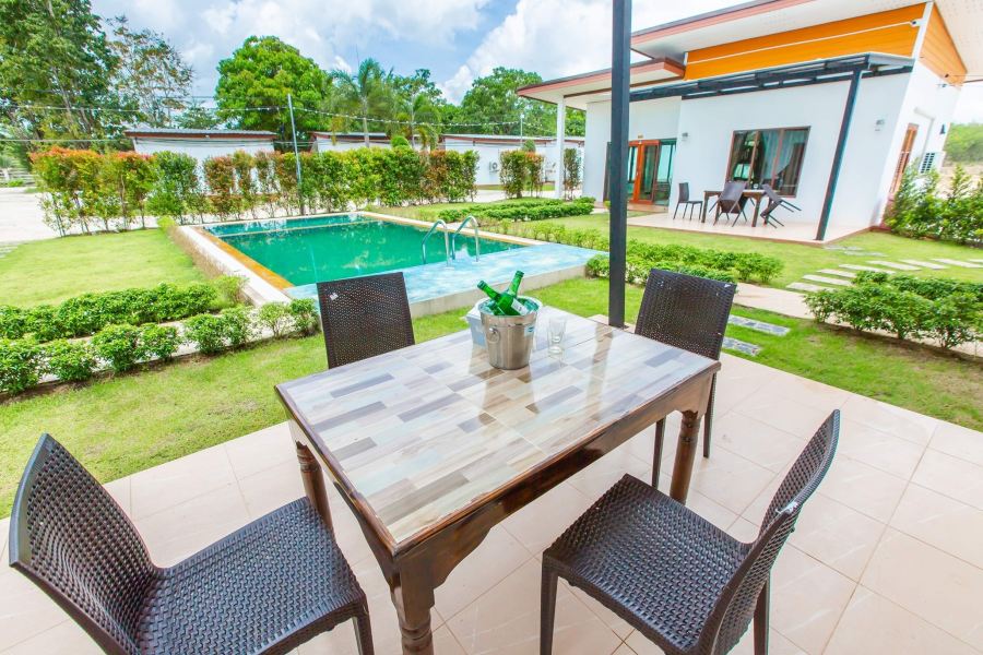 สระว่ายน้ำกลางสวนพร้อมโต๊ะนั่งริมสระที่ Ozone Resort เขาชัยสน