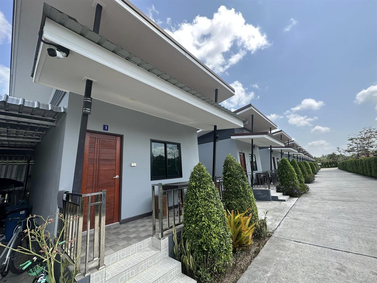 แถวห้องพักเรือนแถวชั้นเดียวของ The Base Resort Phatthalung มีประตูแยกแต่ละห้องและทางเดินปูพื้น