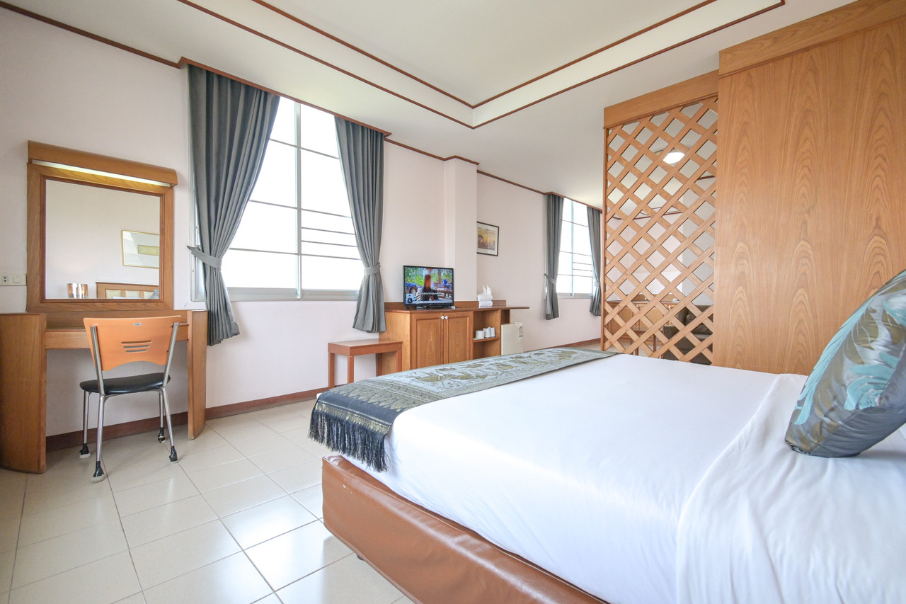 ห้อง Deluxe ของ Rattana Park Hotel พิษณุโลก พร้อมโต๊ะเครื่องแป้งและฉากไม้ระแนง