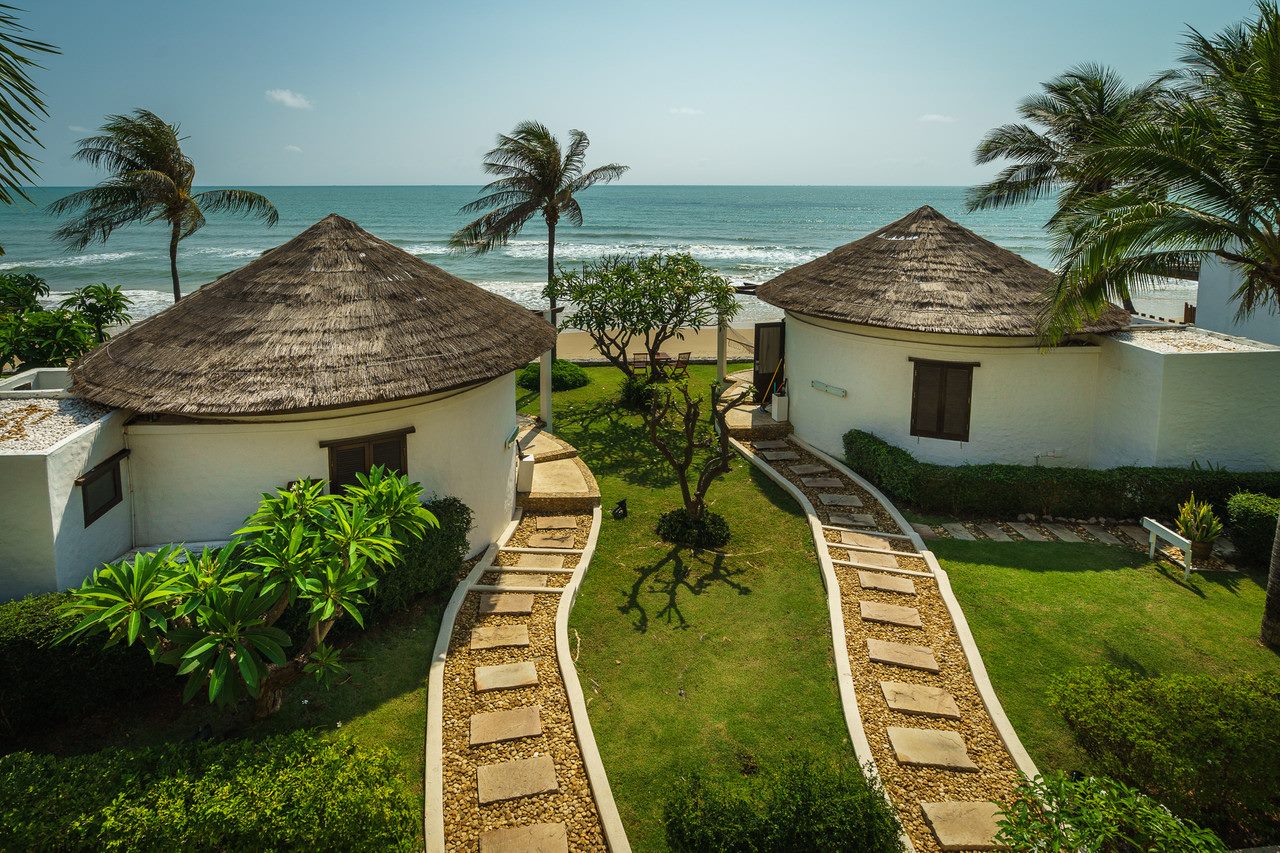 วิลล่าผนังขาวหลังคาจากของ Aleenta Hua Hin - Pranburi เรียงตามทางเดินสู่ชายหาด