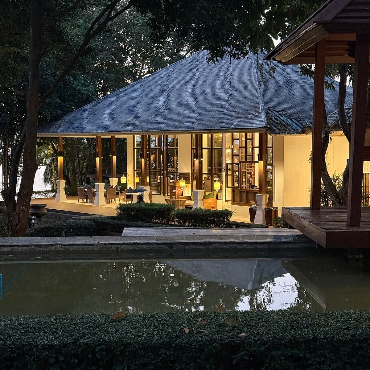 ศาลาร้านอาหารไม้เปิดโล่งยามเย็นพร้อมบ่อน้ำสะท้อนแสงของ The Blue Sky Resort Ranong