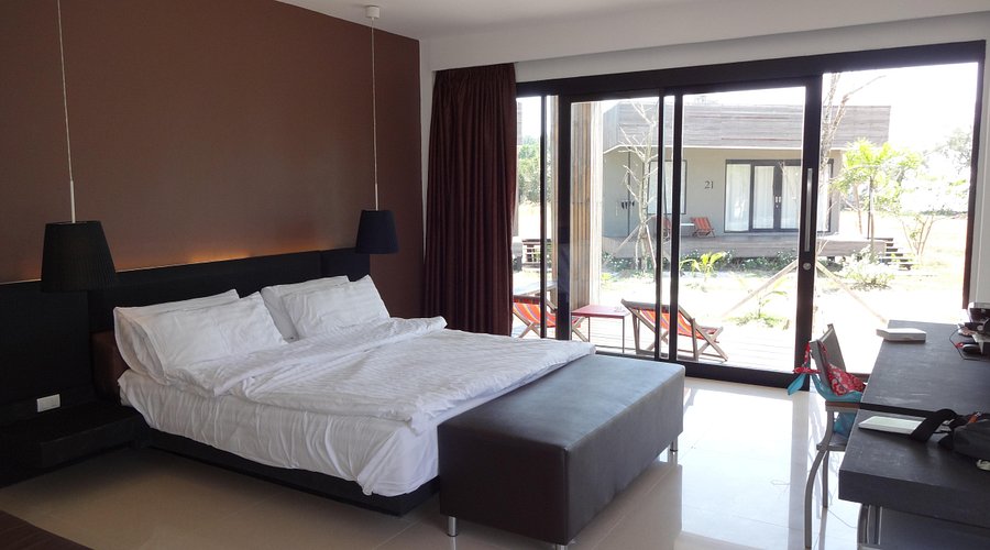 ห้องพักภายในบังกะโล เตียงใหญ่ กระจกบานเลื่อนเปิดออกระเบียงและสวน