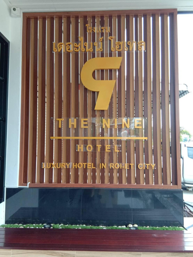 ป้ายหน้าโรงแรม The Nine Hotel Roi-Et บนระแนงไม้ พร้อมโลโก้เลข 9 สีทอง