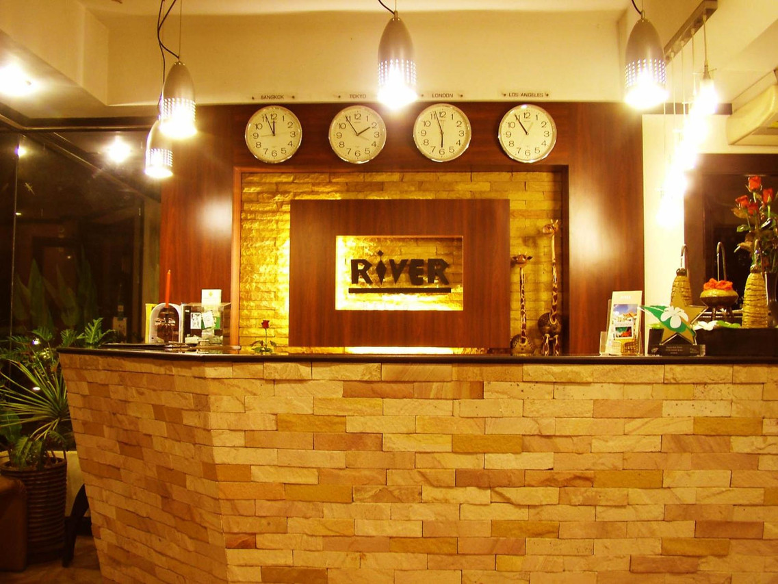 เคาน์เตอร์ต้อนรับผนังหินทรายมีป้าย River ของ River Resort & Spa สระแก้ว