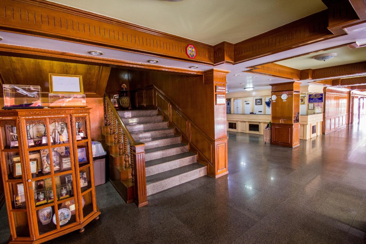 ล็อบบี้ของ Imperial Sakon Hotel เสาไม้ บันไดหินขัด และตู้แสดงของที่ระลึก