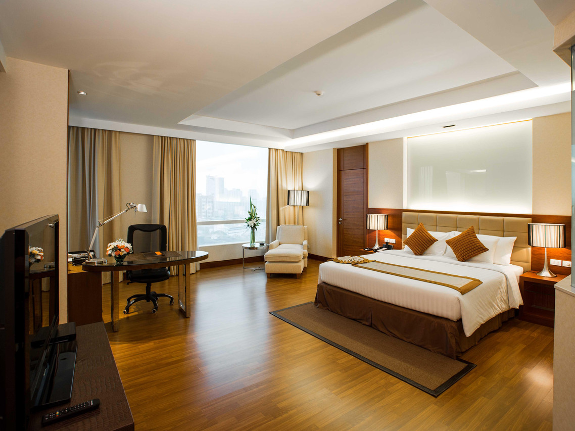 Guest room with wooden floor, floor-to-ceiling window, desk and armchair