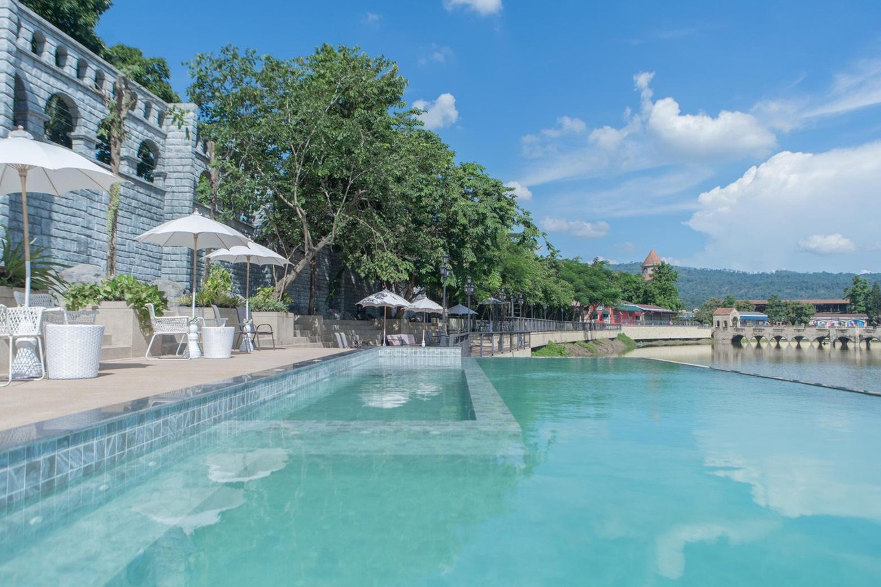 The Verona at Tublan infinity pool running into the lake, stone wall and mountain ridge beyond