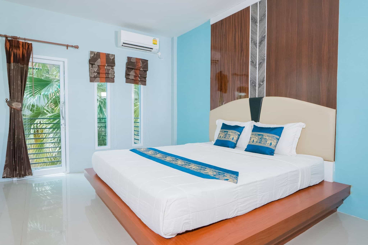 Guest room at Satun Boutique Resort with turquoise wall, large bed and balcony door