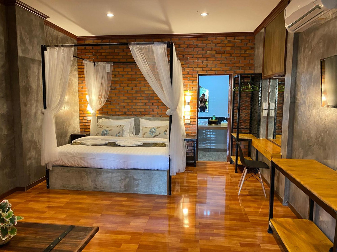 ห้องลอฟต์ผนังอิฐ เตียงโปร่งผ้ามุ้ง พื้นไม้ขัดเงา ที่ Khum Lanna