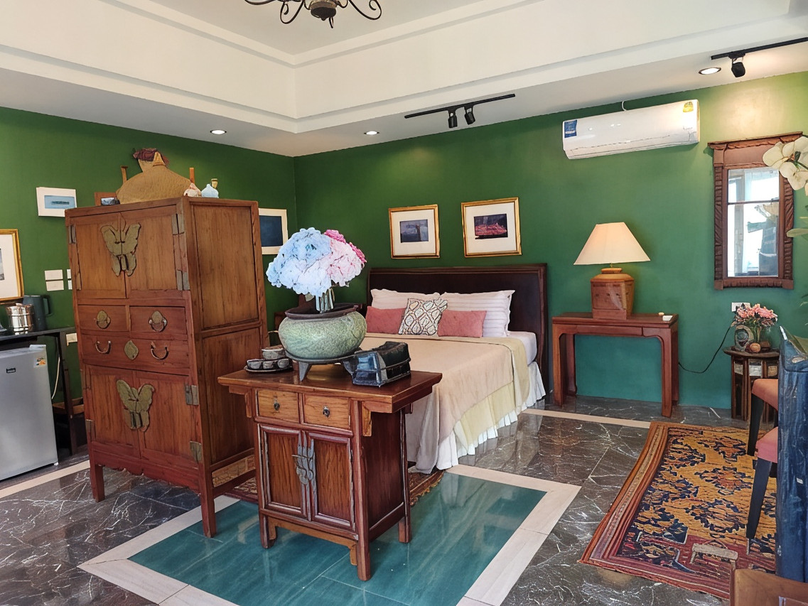 ห้องนอนผนังสีเขียวพร้อมตู้ไม้จีนโบราณและเตียงคิงไซส์ที่ Phu View Hideaway
