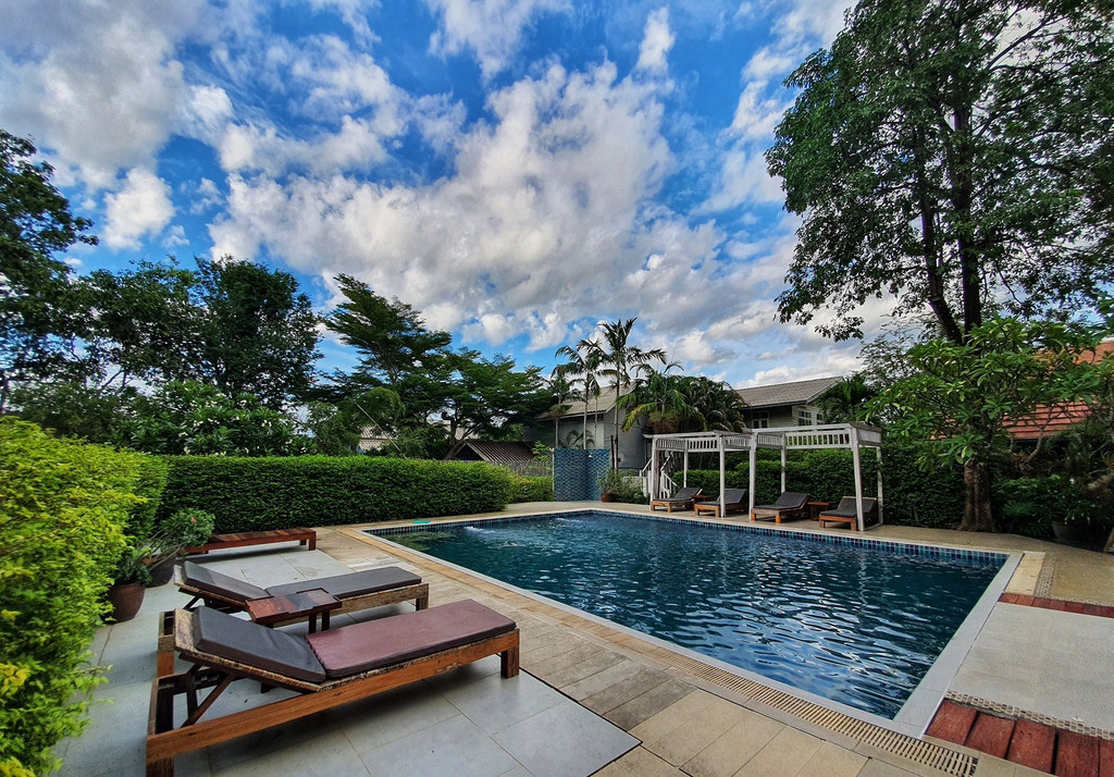 Outdoor garden pool surrounded by greenery and a wooden sala