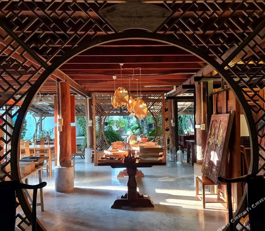 Tharaburi Resort lobby with a carved circular moon-gate archway and antiques