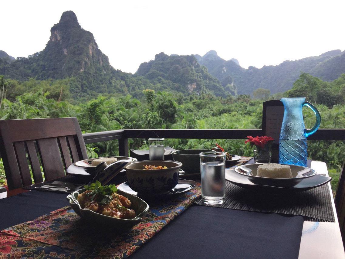 โต๊ะอาหารไทยริมระเบียงร้าน Hornbill มองออกไปเห็นหน้าผาหินปูนเขาสก