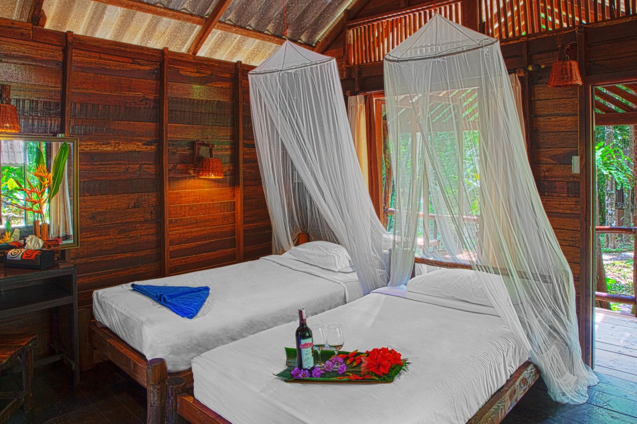 Stilted wooden cottage in the jungle with mosquito-net beds, jungle lodge style