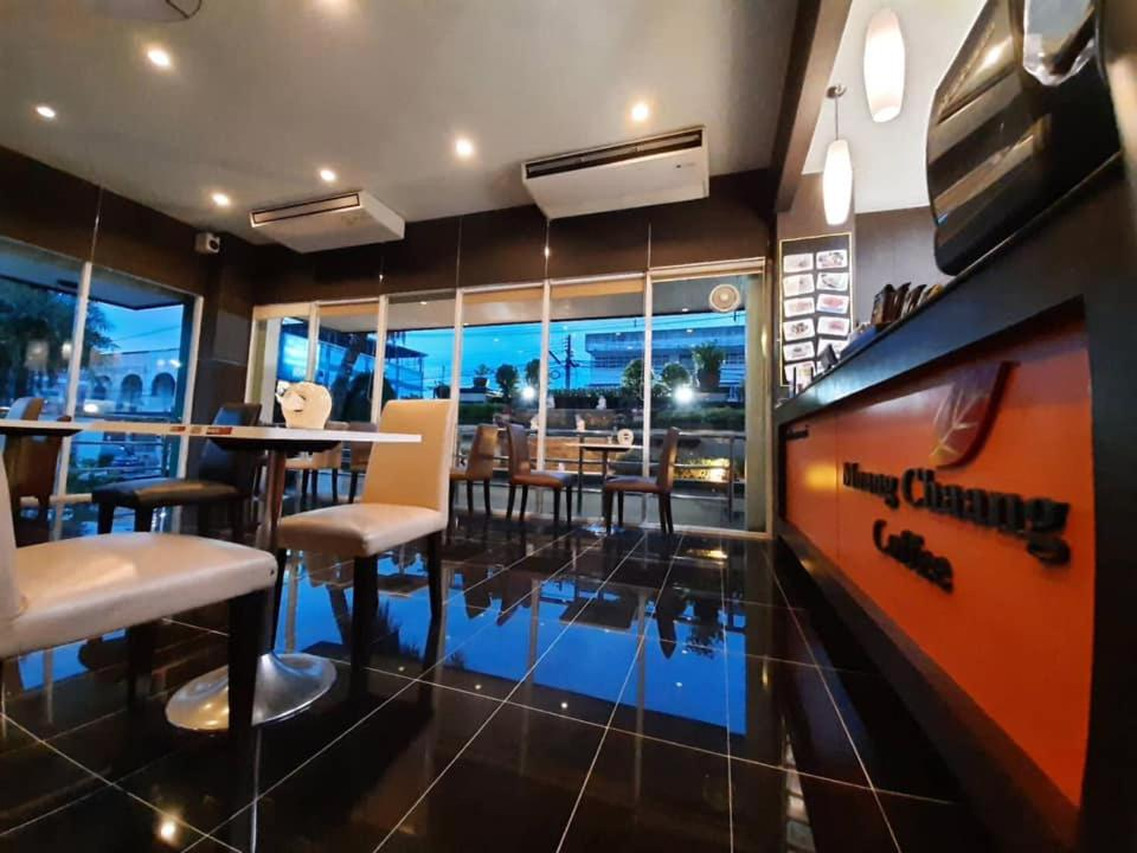 ร้าน Muang Chang Coffee ในโรงแรม โต๊ะไม้กระจกบานใหญ่มองวิวเมือง