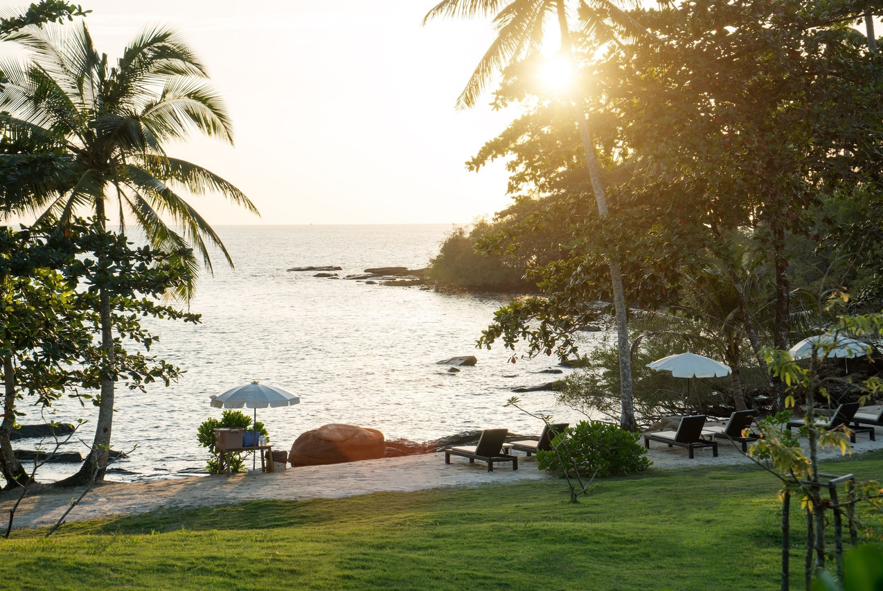 Sunset over the rocky shore with sun loungers on the Shantaa lawn