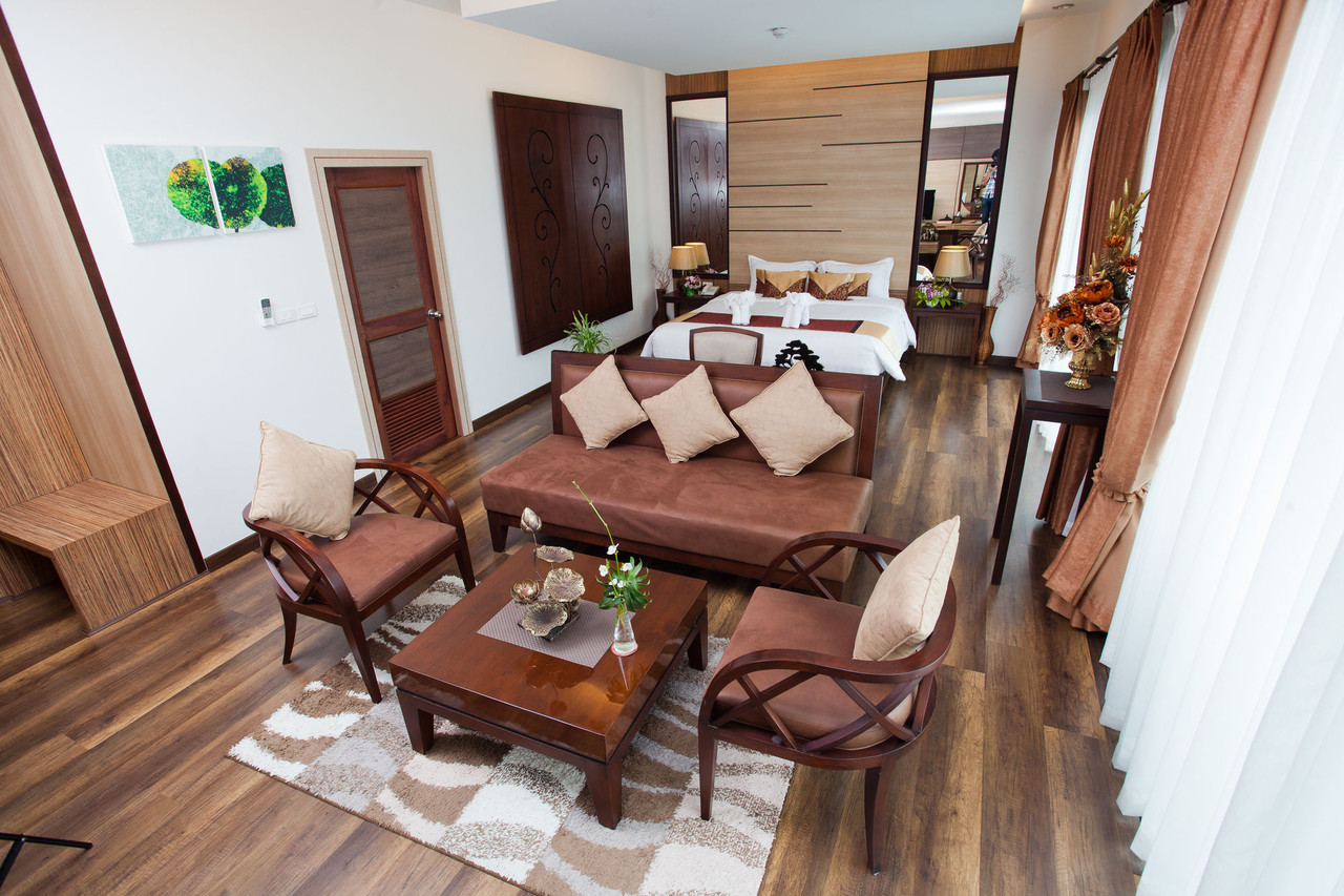 Junior Suite มุมโซฟานั่งเล่น พื้นไม้ และห้องนอนด้านใน