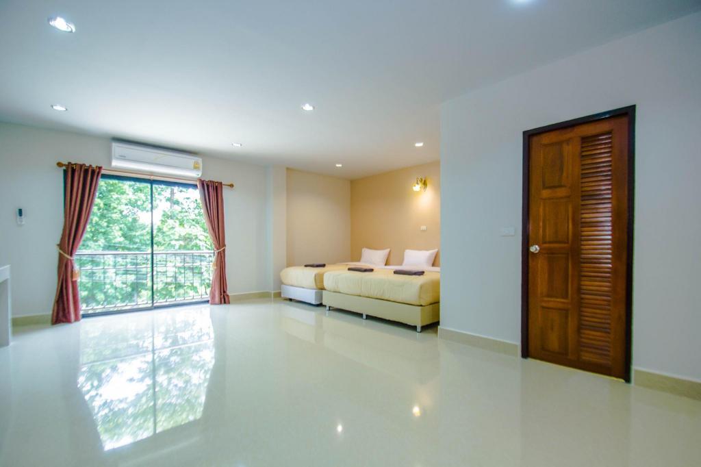 ห้องพักของ Maladee Hotel อุตรดิตถ์ ผนังขาวพื้นกระเบื้องมันวาว เตียงเดี่ยวสองเตียงคาดผ้าสีน้ำตาล ประตูกระจกบานเลื่อนเปิดออกระเบียงเห็นต้นไม้ ตู้เสื้อผ้าไม้บานเกล็ด