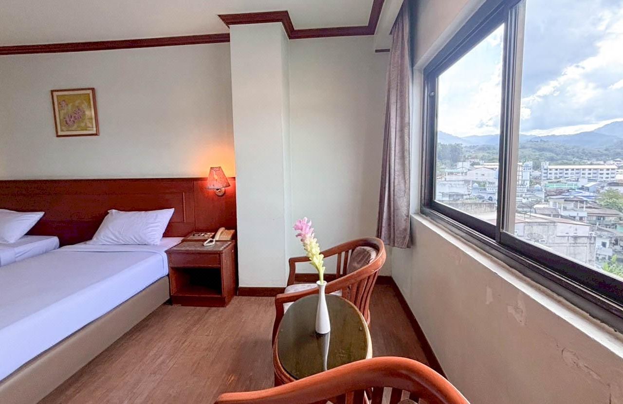 ห้องพัก Sri Betong Hotel มีเตียงและโต๊ะริมหน้าต่างวิวเมืองเบตง