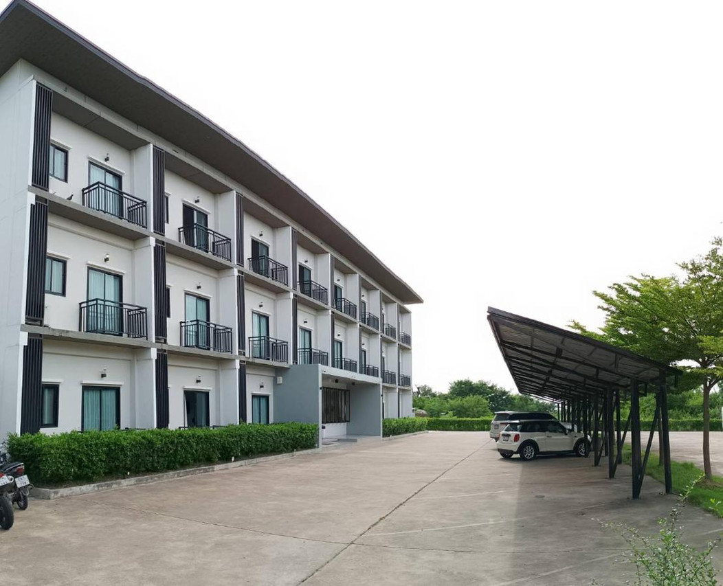 ตึกขาวสามชั้นของ The Zen Hotel Yasothon มุมข้างพร้อมลานจอดรถมีหลังคา